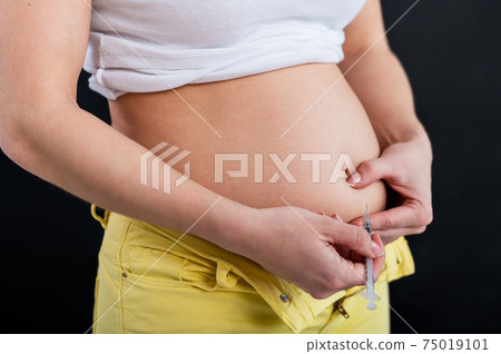 Faceless woman injects insulin into her stomach. Close-up of a syringe pen. Subcutaneous administration is a cure for diabetes. Faceless woman injects insulin into her stomach. Close-up of a syringe pen. Subcutaneous administration is a cure for diabetes. 75019101