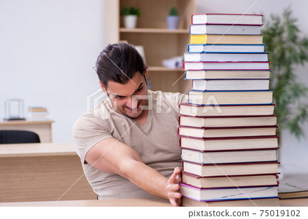 Young male student preparing for exams at library Young male student preparing for exams at library 75019102