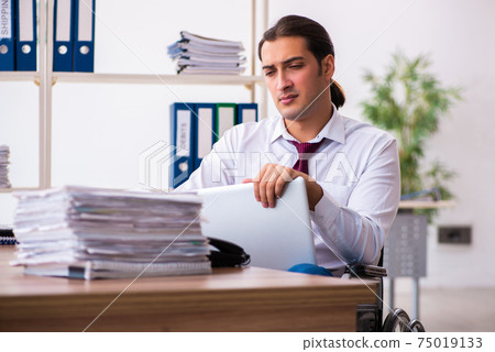 Young male employee after accident in wheel-chair at workplace 75019133
