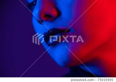 Close-up portrait of beautiful young woman with short hair in neon light. Girl with sensual lips in ultraviolet light. 75019305