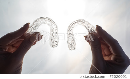 Transparent trays for correcting teeth in female hands. Removable plastic retainers 75020091