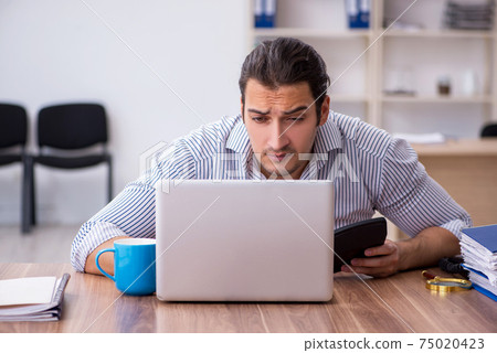 Young male bookkeeper working in the office 75020423