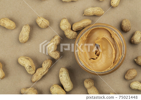 Creamy and smooth peanut butter in jar on paper table. Creamy and smooth peanut butter in jar on paper table. 75021448