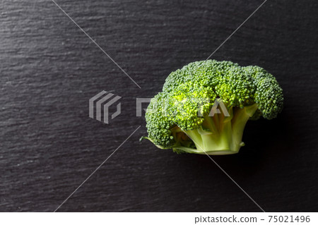 Fresh broccoli on a black cutting board. Healthy food concept. 75021496