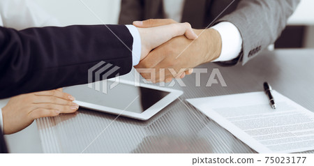Handshake as successful negotiation ending, close-up. Unknown business people shaking hands after contract signing in modern office 75023177