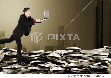 Asian businessman running while holding laptop 75023205