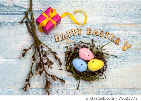 Gift boxes with ribbons. Happy Easter. Willow twigs. Holy Easter. Blue turquoise background. Easter eggs in the nest. 75023372
