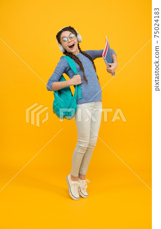 Girl loves music. Happy child listen to music yellow background. 75024183