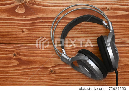 Vintage headphones for listening to sound and music on a wooden background 75024360