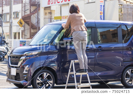 A woman wiping the roof of a car after a car wash at a car wash on a warm spring day A woman wiping the roof of a car after a car wash at a car wash on a warm spring day 75024715