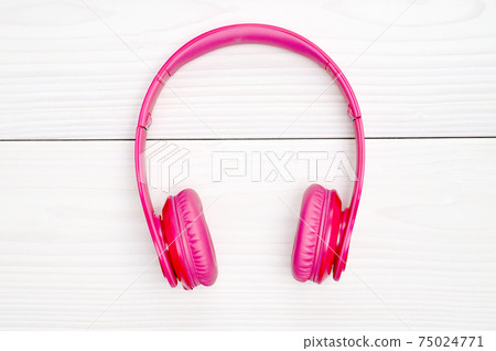 Pink headphones for listening to sound and music on a wooden background 75024771