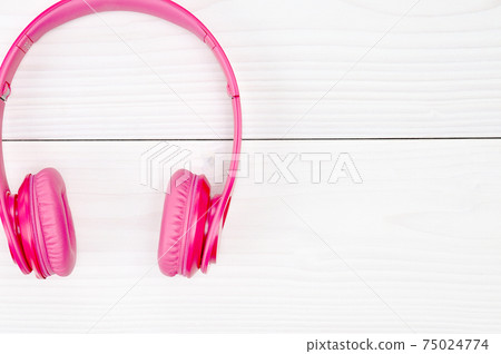 Pink headphones for listening to sound and music on a wooden background 75024774