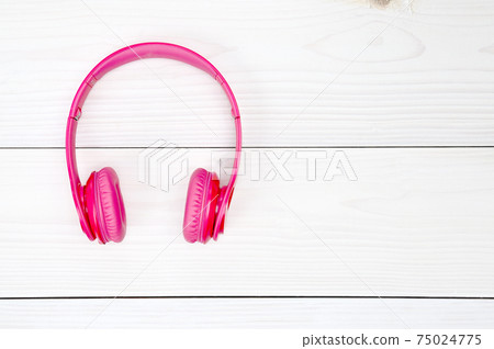 Pink headphones for listening to sound and music on a wooden background 75024775