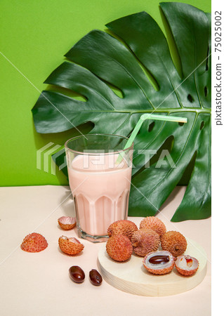 Fresh smoothie and lychee fruits on pink table 75025002