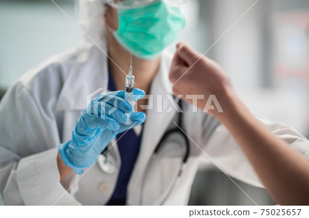 A young nurse releases air and excess medicine from the syringe before the injection 75025657