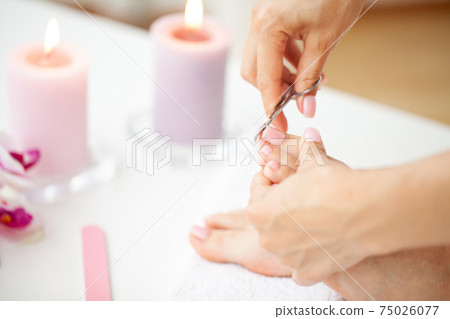Cozy home spa, young woman doing pedicure on her feet nails. 75026077