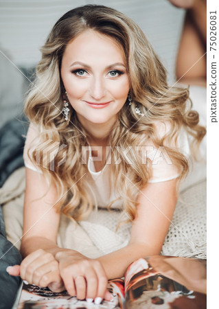 Pretty girl lies on her bed, reads an interesting 75026081