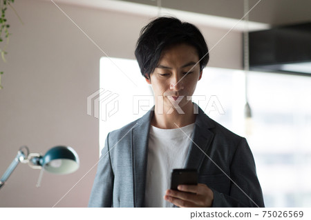 A man looking at a smartphone in the room A man looking at a smartphone in the room 75026569