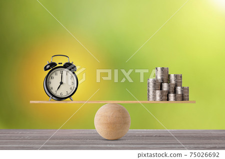 Alarm clock on seesaw balancing with stacking coins money on wooden table, meaning of business investment and saving growth with time for advertising concept. 75026692