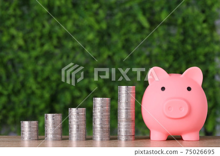 Business investment and saving growth for advertising concept. Stacking coin growing with pink piggy bank on green nature background, meaning of growing or saving or earning money Business investment and saving growth for advertising concept. Stacking coin growing with pink piggy bank on green nature background, meaning of growing or saving or earning money 75026695