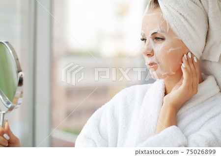 Pretty girl wearing face care mask at home Pretty girl wearing face care mask at home 75026899