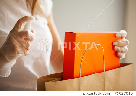 Close up of woman in protective gloves disinfecting shopping 75027010