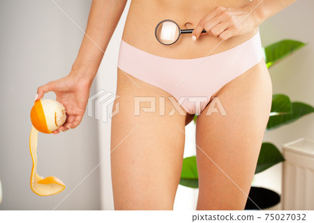 Woman with sport body holding orange near her leg, anti-cellulite concept Woman with sport body holding orange near her leg, anti-cellulite concept 75027032