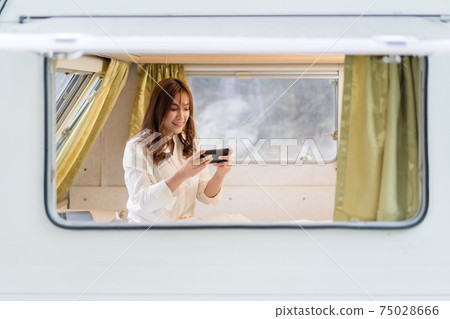 woman using smartphone on bed of a camper RV van motorhome woman using smartphone on bed of a camper RV van motorhome 75028666