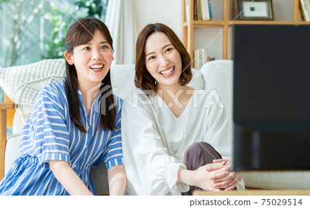 A young woman watching TV with her friends 75029514