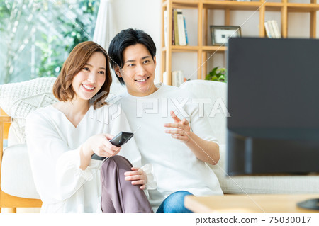 Young couple watching TV in the living room 75030017