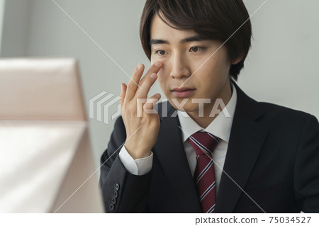 Image of young men in suits applying BB cream, men's makeup 75034527