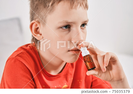 Blond Boy drips nose drops from runny nose. Treatment of colds and allergic rhinitis. Selective focus Blond Boy drips nose drops from runny nose. Treatment of colds and allergic rhinitis. Selective focus 75035379