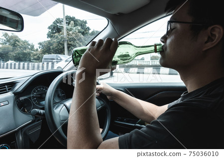Man Driver Drinking Alcohol and Drunk While Driving a Car, Drunken Man Lose Control and Visual Visibility During Drive a Vehicle Car. Illegal Violation and Accident Risk. Man Driver Drinking Alcohol and Drunk While Driving a Car, Drunken Man Lose Control and Visual Visibility During Drive a Vehicle Car. Illegal Violation and Accident Risk. 75036010