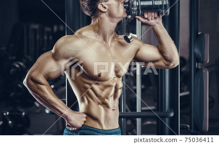 Bodybuilder drinking water after fitness workout. 75036411