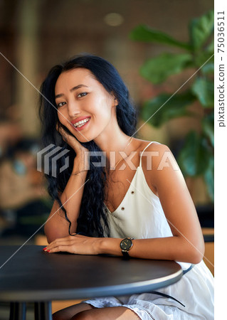 Young beautiful asian woman sitting at the table in cafe Young beautiful asian woman sitting at the table in cafe 75036511