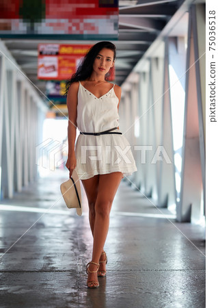 Outdoor fashion portrait of young woman walking in the corridor 75036518