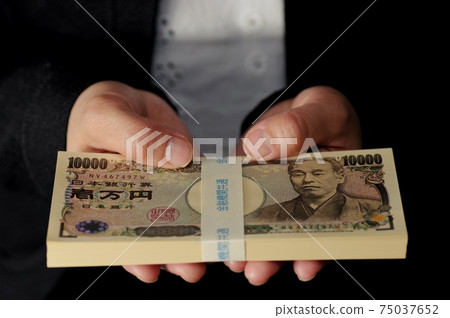 Female hand holding a wad of bills 75037652