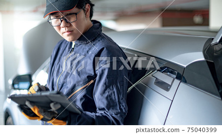 Asian auto mechanic checking car in garage Asian auto mechanic checking car in garage 75040399
