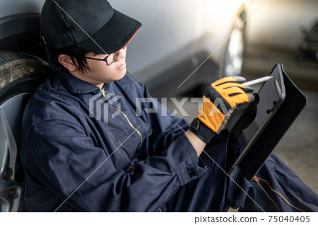 Asian auto mechanic checking the car wheel using tablet 75040405