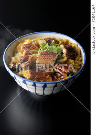 A hot eel bowl with eel kabayaki bound with eggs on a black background 75041164