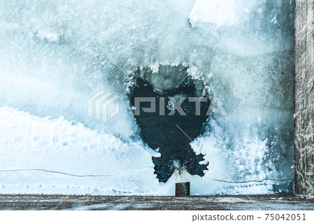 Rusty sewage pipe draining water into frozen river Rusty sewage pipe draining water into frozen river 75042051