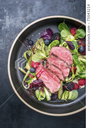 Traditional barbecue dry aged sliced filet steak with lettuce and forest fruits Traditional barbecue dry aged sliced filet steak with lettuce and forest fruits 75043214