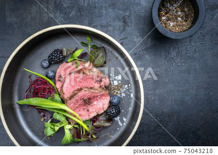 Traditional barbecue dry aged sliced fillet steak with wild garlic and fruits  75043218