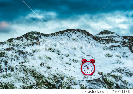 Alarm clock on a rock covered by snow Alarm clock on a rock covered by snow 75043388
