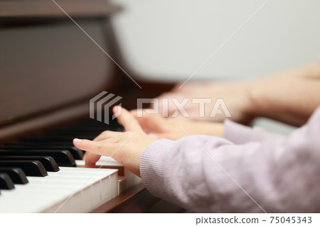 5-year-old girl and mom playing an upright piano 75045343
