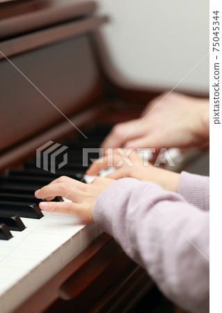 5-year-old girl and mom playing an upright piano 75045344