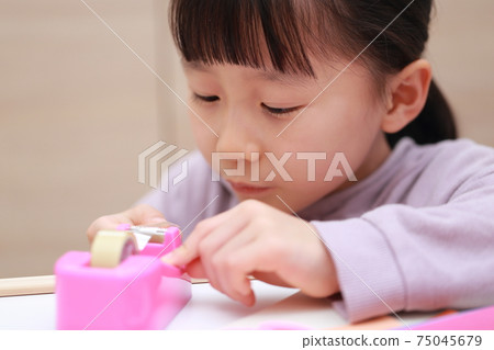 Girl who cuts and works on cellophane tape 75045679