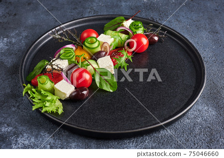 Fresh greek salad with tomato, cucumber, bel pepper , olives and feta cheese on black plate Fresh greek salad with tomato, cucumber, bel pepper , olives and feta cheese on black plate 75046660