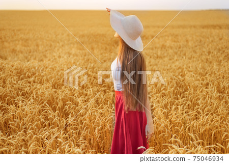 Young woman in hat with beautiful long hair on ripe wheat background. Young woman in hat with beautiful long hair on ripe wheat background. 75046934