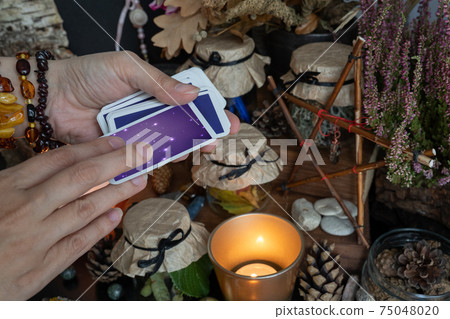 Woman hand is holding deck of tarot or oracle cards doing fortunetelling. 75048020